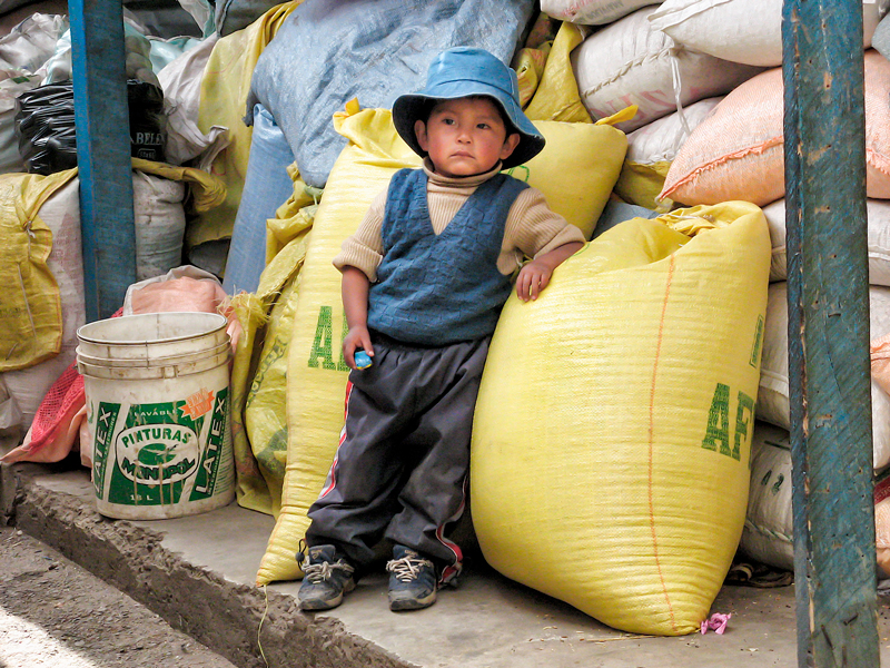 Young Bolivian boy leaning on grain sacks in La Paz Bolivia